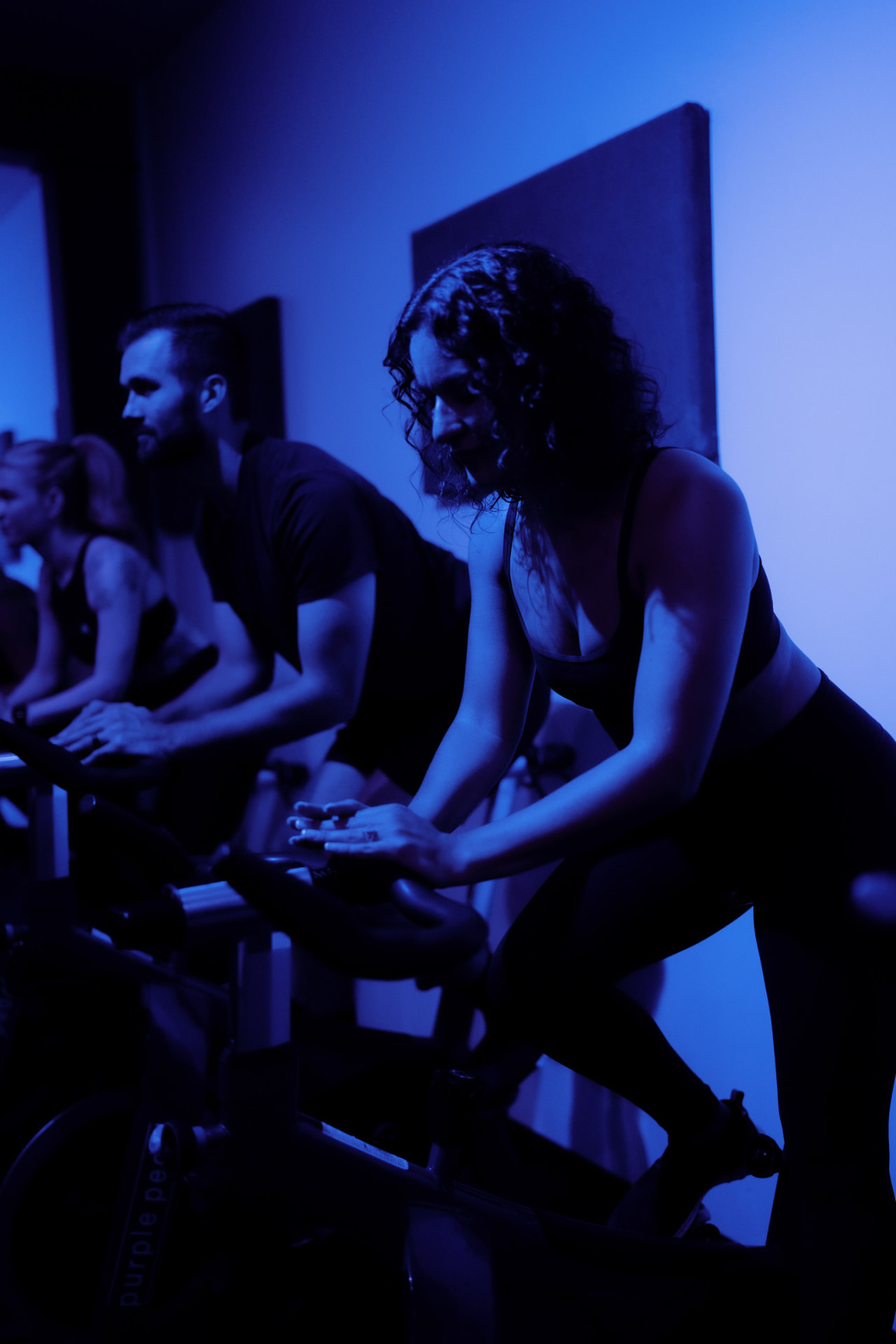 Riders deep in a Purple Pedal class under moody studio lighting